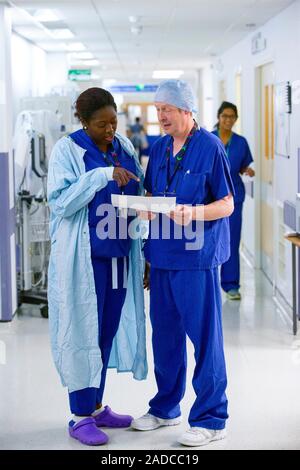 Hospital surgeons talking in a corridor. Photographed in the UK. Stock Photo