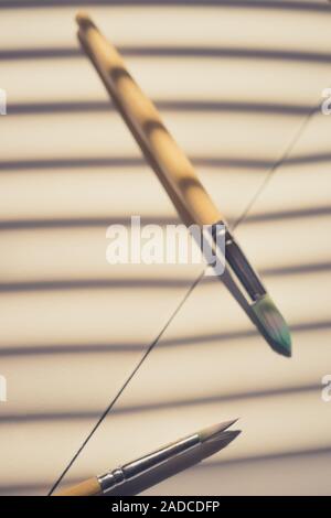 Two used different brushes for painting on the sunny paper with shadow stripes. Stock Photo