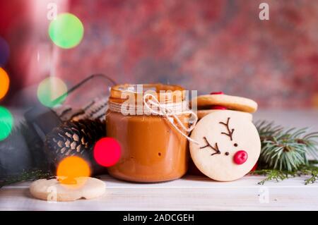 Tasty and fragrant chocolate chip cookies are crushed with powdered sugar, with multi-colored lights on the table. Merry Christmas Stock Photo