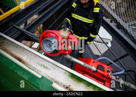 Details with the hands of a firefighter holding a fire suppression system (hydrant) on a hospital helipad. Stock Photo