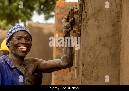 Construction worker plastering a wall, using a finishing trowel to smooth the surface. Photographed in Lacor, Gulu, Uganda. Stock Photo
