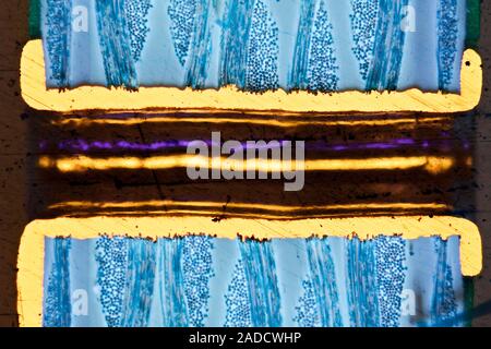 Light micrograph of a section through a computer multilayer printed circuit board (PCB) with a via. A via is an electrical connection between layers i Stock Photo