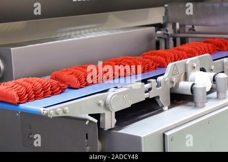 Molding system for the production of meat products at the factory. The machine prepares minced meat. The machine divides portions by weight and spread Stock Photo