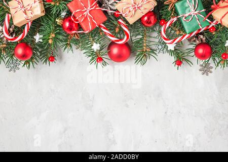 Christmas or Happy New Year background made of fir tree branches, holiday decorations, candy and gift boxes on concrete background. flat lay. top view Stock Photo