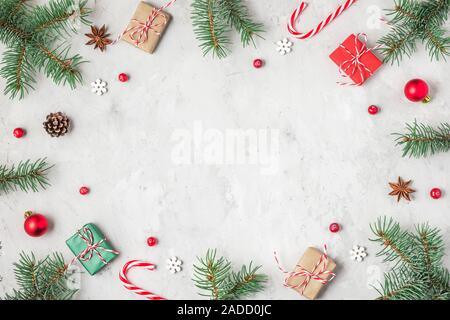 Christmas or Happy New Year composition. Frame made of fir tree branches, holiday decorations, candy and gift boxes on concrete background. flat lay. Stock Photo