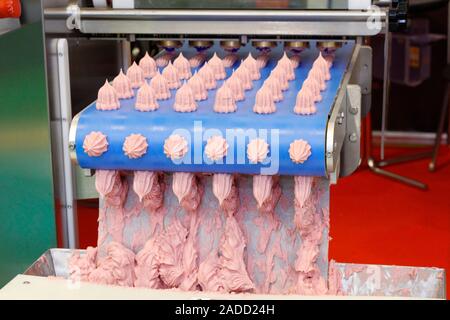 Making sweet cakes on a production line. A baking machine with a conveyor on which confectionery is located. The operation of the machine is shown. Mo Stock Photo