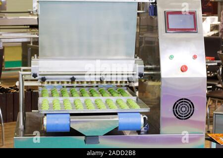 Making sweet cakes on a production line. A baking machine with a conveyor on which confectionery is located. The operation of the machine is shown. Mo Stock Photo