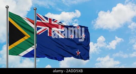 South Africa and New Zealand flag waving in the wind against white cloudy blue sky together. Diplomacy concept, international relations. Stock Photo