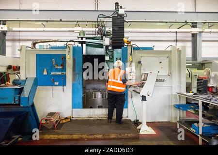 Metalworks. Worker operating a CNC (computer numerical control) lathe at a metalworks. Photographed at Ecosteel, Scotland, UK. Stock Photo
