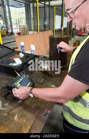 Metalworks. Worker using an ultrasonic testing machine at a metalworks. This device uses ultrasound to ensure products have the right balance of compo Stock Photo