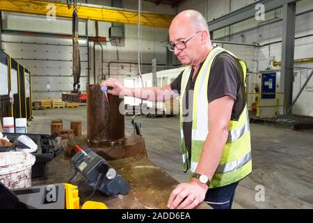 Metalworks. Worker using an ultrasonic testing machine at a metalworks. This device uses ultrasound to ensure products have the right balance of compo Stock Photo