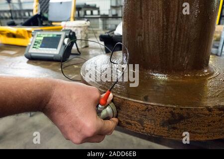 Metalworks. Worker using an ultrasonic testing machine at a metalworks. This device uses ultrasound to ensure products have the right balance of compo Stock Photo