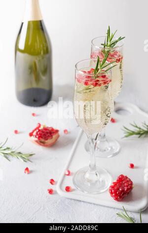 Two glass of Pomegranate champagne Christmas holiday cocktail with rosemary spig, champagne, club soda on grey table. Xmas drink. Stock Photo