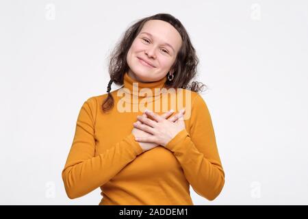 Happy delighted woman in yellow clothes is pleased to receive a compliment fromm her coworkers. Studio shot. Positive facial human emotion. Stock Photo