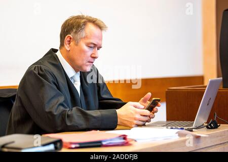 Detmold, Germany. 04th Dec, 2019. The sworn Carsten Ernst looks at his mobile phone. The public prosecutor's office in Detmold accuses the 'driving licence king' of 505 cases of fraud, which are said to have led to a total loss of almost 650,000 euros. Together with his wife he is said to have committed another 158 similar acts. Credit: David Inderlied/dpa/Alamy Live News Stock Photo