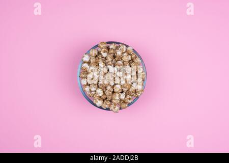 Caramel sweet popcorn bowl isolated on pink background top view. Frame composition with copy space. Stock Photo