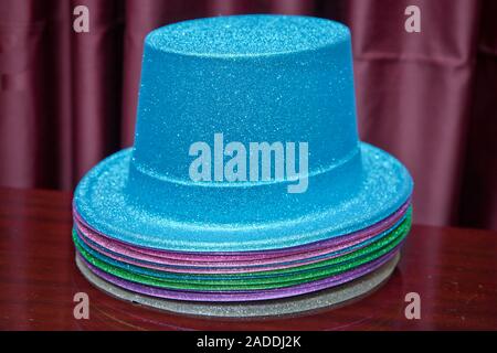 Blue metallic party hat . Blue magician performer hat on a isolated red background . Colorfull magical hats. Stock Photo