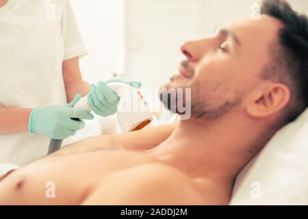 Selective focus of the laser hair removal tool in the hand of medical worker Stock Photo