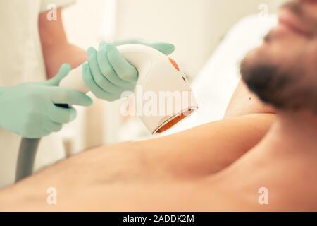Close up of laser hair removal tool in hands of professional doctor