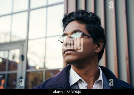 Young handsome Indian man in an office suit and white shirt, with glasses Stock Photo