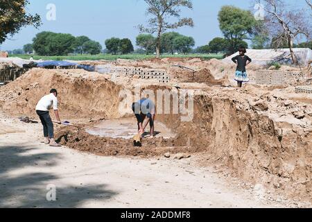 Mud brick industry. Workers preparing clay and mud that will be shaped and either dried in the sun or baked in a kiln to produce bricks for use in the Stock Photo