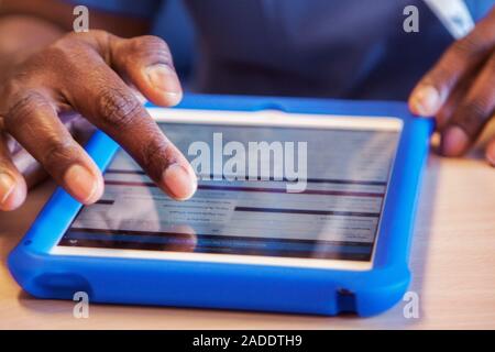 This is a real situation. Image not to be used in a defamatory context. MODEL RELEASED. Patient care being recorded on a tablet computer by an associa Stock Photo