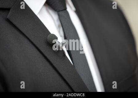 Close up picture of a  clip on microphone on a black suit Stock Photo
