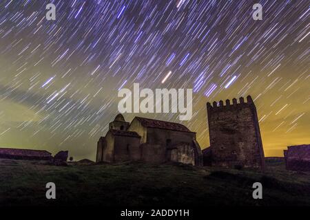 Star trails over Noudar Castle. Time-exposure image of stars forming light trails in the sky over the church and tower of Noudar Castle (completed in Stock Photo