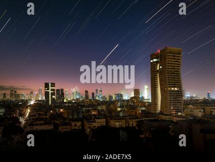 Star trails and light pollution over Tel Aviv, Israel. Time-exposure image of star trails formed in the night sky above buildings in Tel Aviv, Israel. Stock Photo