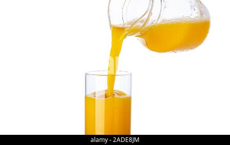 Orange juice pouring from pitcher into glass isolated on white background Stock Photo