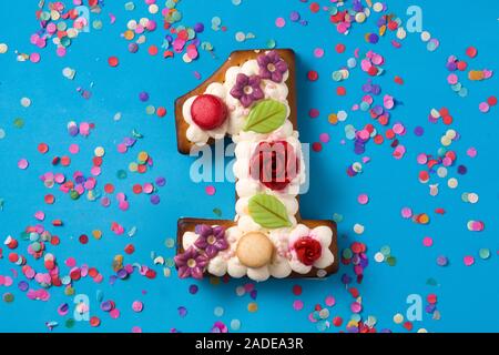Number one cake decorated with flowers, macarons on blue background Stock Photo