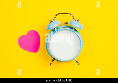 Vintage blue blank alarm clock on a yellow background with pink sticker Stock Photo