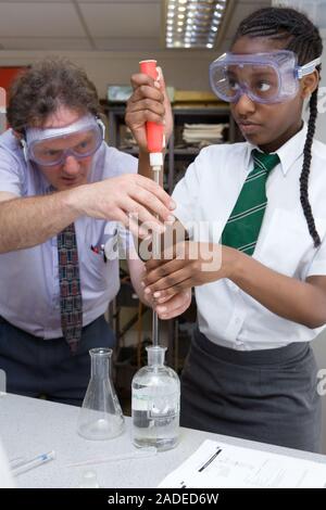 Secondary School teacher helping a student during a titration chemistry experiment. Stock Photo