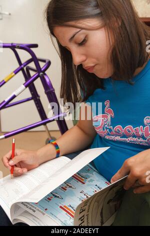 Young woman with cerebral palsy, who uses a walking frame, studying. Stock Photo