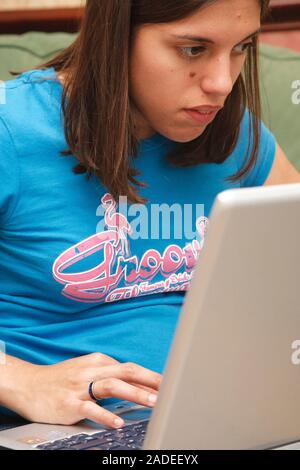 Young woman with cerebral palsy, who uses a walking frame, studying on laptop computer. Stock Photo