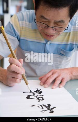 Man doing Chinese art writing using brush pen. Stock Photo