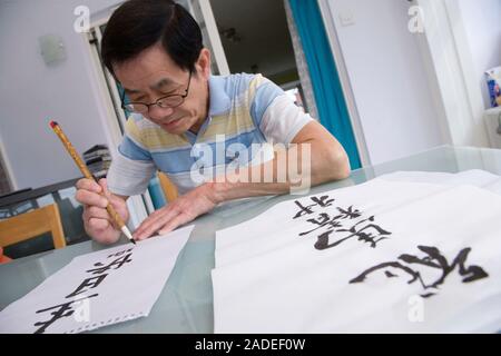 Man doing Chinese art writing using brush pen. Stock Photo