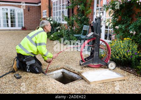 BUCKINGHAM, UK - October 16, 2019. A professional drain cleaning engineer inspects a blocked household drain Stock Photo