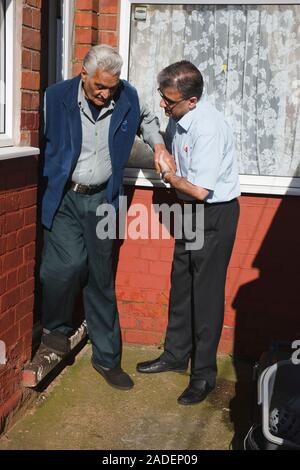 Son helping elderly south Asian father down step. Stock Photo