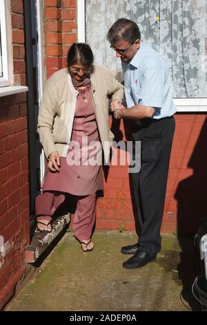 Son helping elderly south Asian mother down step. Stock Photo