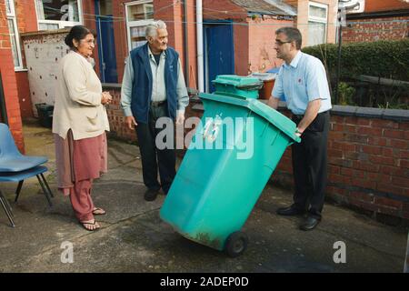 Son helping elderly south Asian parents by putting bin out. Stock Photo