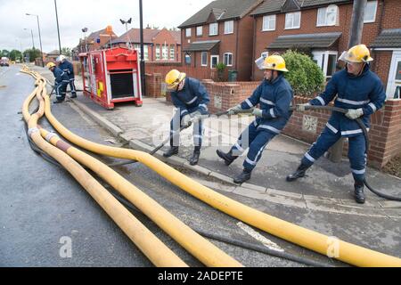 Members of the fire rescue service moving high volume pumps (HVP) used to drain away flood water and dump it into nearby rivers and lakes following th Stock Photo