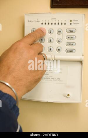 Close-up of hand of older man setting his house alarm. Stock Photo