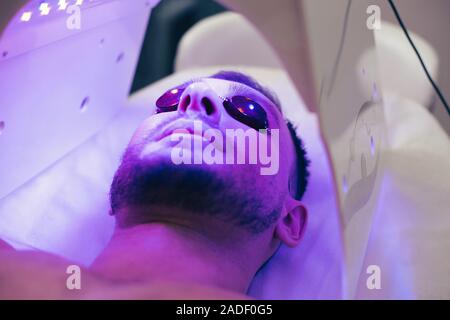 Young man smiling in solarium while getting suntan Stock Photo