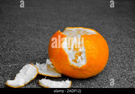 An orange light tangerine on a table, the paring is peeled Stock Photo