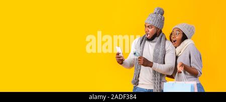 Stunned african couple making shopping by phone, online banking Stock Photo