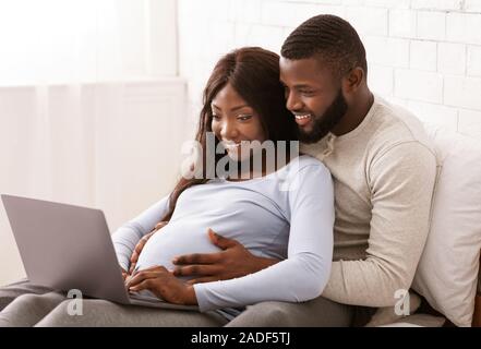 Close up of black pregnant couple using laptop at home Stock Photo