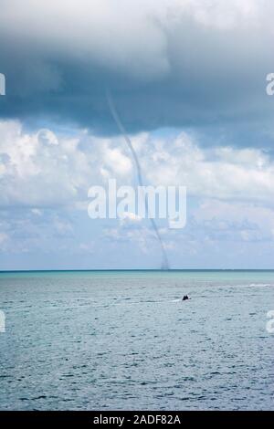 Waterspout forming over the sea. This non-tornadic formation is a funnel-shaped vortex that occurs over a body of coastal water and is connected to a Stock Photo