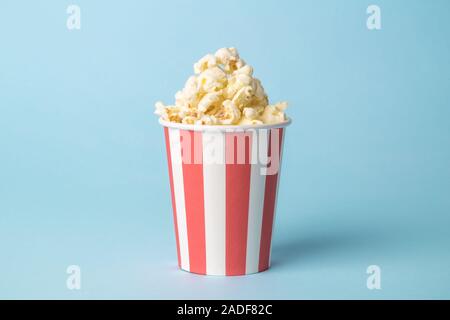 Popcorn in paper cup against pastel blue background minimal creative food concept. Stock Photo