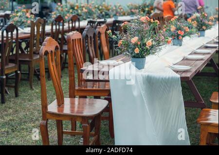 Rustic wedding style, Wooden dining table with flowers decoration and tableware set Stock Photo